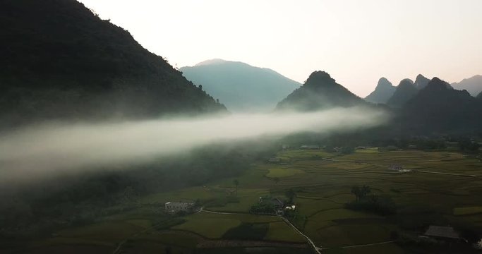 Moody landscape with mountains over the clouds. Dark orbiting, aerial shot above hidden village, Lam Thuong valley, Vietnam