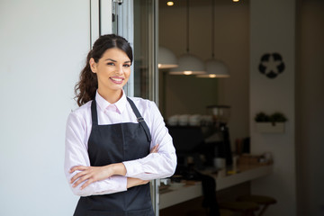 Beautiful waitress in apron smiling, showing welcome to coffee shop