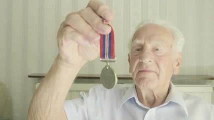 Senior caucasian man looking at an old medal themes of retired memories respect honour