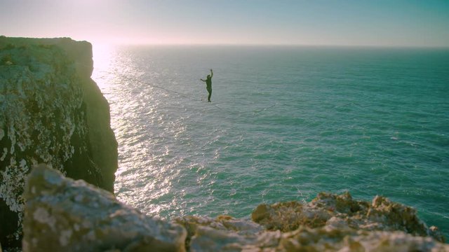 Slackliner loses his balance on a line and falls, shot over water