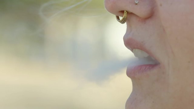 Closeup of a Caucasian woman taking a drag from a vape, 60 fps