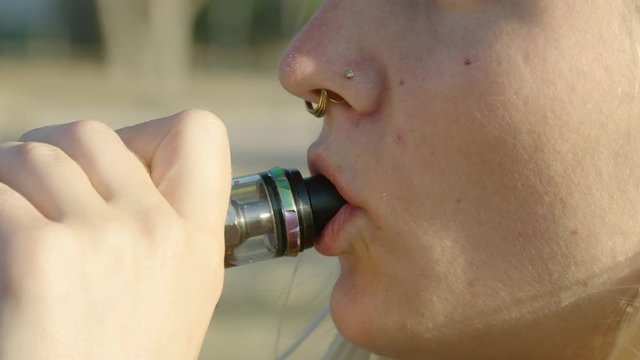 Caucasian woman taking a hit from a vape