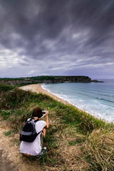 Woman photographing the beach of Langre and the cape of Galizano, Ribamontán al Mar, Cantabria. Spain