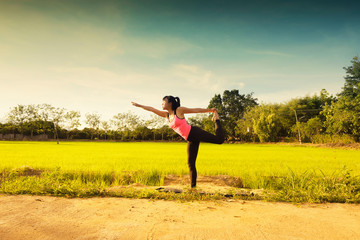 Yoga Woman feet up practicing yoga at the rice fields sunset time