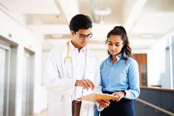 Arzt im Krankenhaus zeigt einer jungen Frau etwas auf seinem Klemmbrett