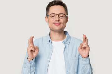 Head shot studio portrait guy with closed eyes crossing fingers