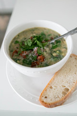 Zuppa Toscana Soup on Table with Bread, White Background