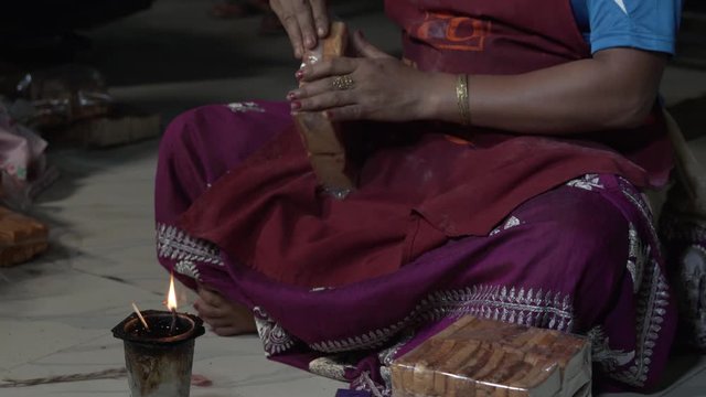 Indian women sitting on the floor and sealing a plastic bread package with candle flame