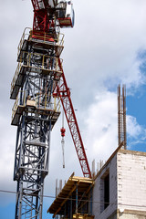 Fototapeta na wymiar Close-up of the top of a blue tower crane near a new building against a blue sky, selective focus
