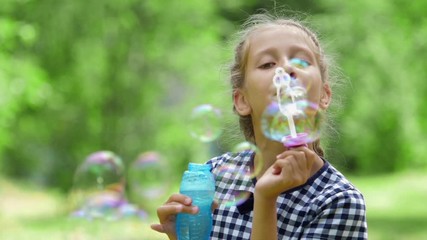 Girl playing with soap bubbles outdoor.