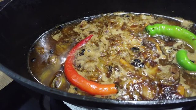 Cooking of boiling traditional asian pilau with lamb meat, rice and red and green chili peppers. 4K clip