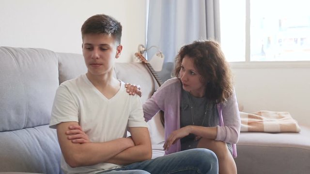 Worried mother having serious conversation with teen boy at home