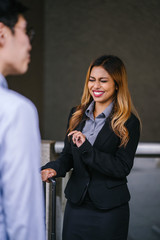 An office lady is telling a story to his colleague. She looks very attractive in her corporate attire.