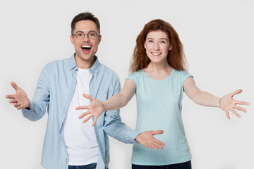 Excited couple looking at camera raise hands welcoming greeting gesture