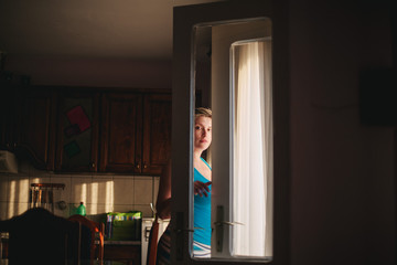 Young woman standing behind a glass door in a dramatically lighted indoor space 