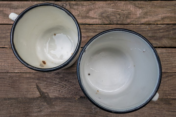 two vintage enameled wet mugs on the table