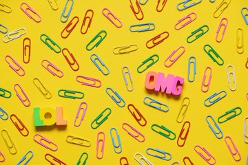 Colorful paperclips on yellow background and omg lol letters