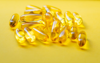 Fish oil capsules on a yellow background. Omega 3, omega 6, omega 9. Top view, copy space.