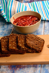 The soup in the plate on the table. Sliced grain bread. Lunch in rustic style.
