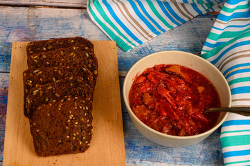 The soup in the plate on the table. Sliced grain bread. Lunch in rustic style.