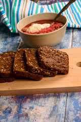 The soup in the plate on the table. Sliced grain bread. Lunch in rustic style.