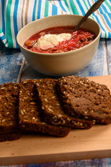 The soup in the plate on the table. Sliced grain bread. Lunch in rustic style.