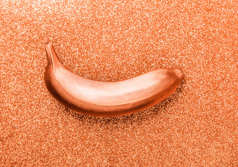Bronze colour food, copper banana on glitter or shimmer background. Trendy tropical flat lay....