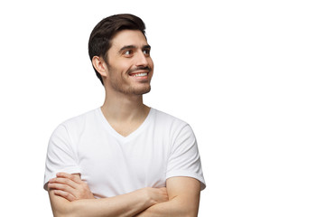 Fototapeta premium Portrait of young man with crossed arms and dreamy cheerful expression, isolated on white background with copy space