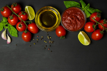 Italian food ingredients for tomato paste: tomatoes, lime, olive oil, Basil, pepper on a black background. Healthy food concept, plant background, natural eco-products, organic food, vegetarian, veg