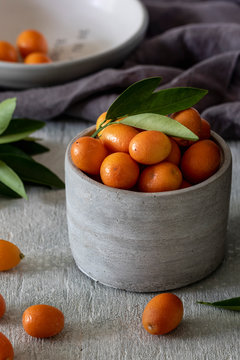 Fresh kumquat in gray bowl with green leaves