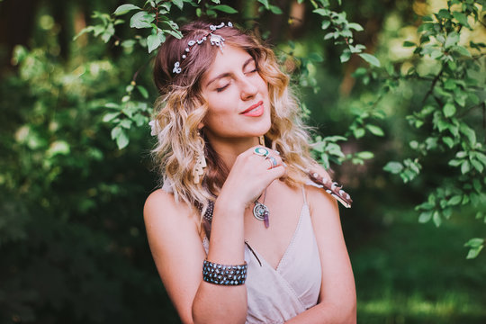 Bohemian hippie girl in white dress. Woman hands with lot of boho style jewelry, blue rings,silver bracelets and henna tattoo. Outdoor summer day in forest.