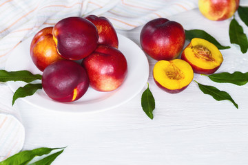 ripe fresh nectarines in a white plate on a white background. crop of nectarines on the table.