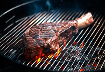 Angus beef tomahawk steak being grilled on a BBQ