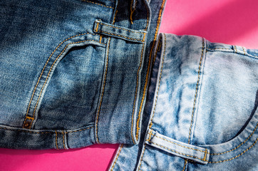 Blue jeans - front pockets close-up on a bright pink background. The concept of fashion, style, universal clothing. Place for text, flat lay, minimalism.