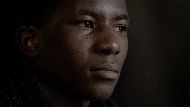 confident pensive american african man in the dark,turning and looking at camera