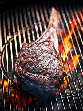 Angus beef tomahawk steak being grilled on a BBQ