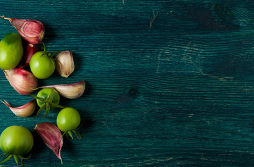 Tomatoes on the background. Tomatoes, garlic on a wooden surface. View from above. Fresh vegetables. copy space.