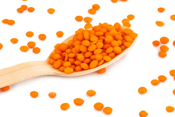 red lentils on wooden spoon isolated on white background