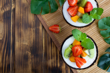 Fruit  salad in the  half coconut on the tropical background. Top view.Copy space.