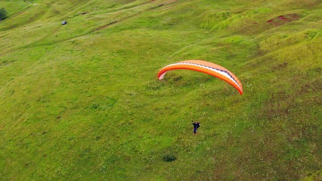 Extreme sport concept. A person is flying the parafoil along the green meadow