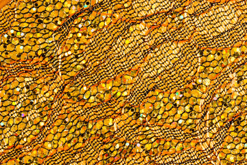 Abstract textured background of netting fabric with gold sequins