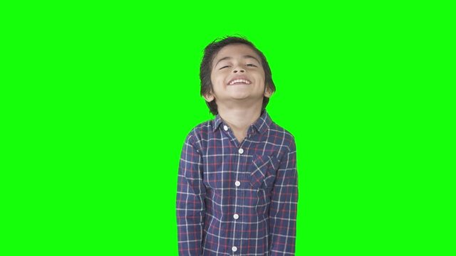 Cute little boy with casual clothes standing and posing in the studio. Shot in 4k resolution with green screen background