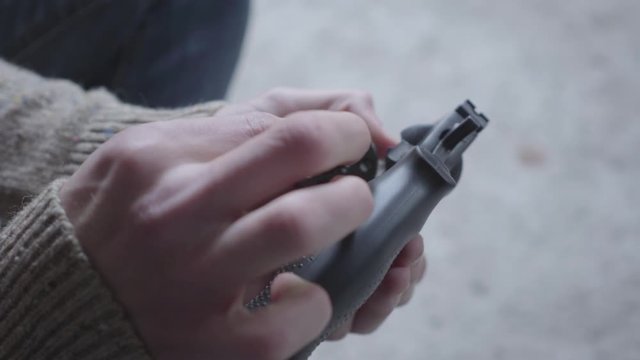 Hands of young man dismantle and clean the gun close-up. The guy preparing to kill human or commit suicide