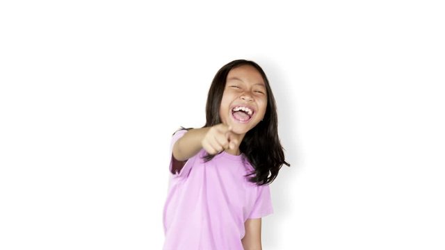 Female elementary school student looks mocking someone while laughing and pointing at the camera in the studio, isolated on white background. Shot in 4k resolution