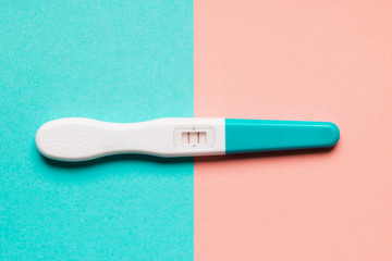 Positive blue plastic pregnancy test on pink and blue background