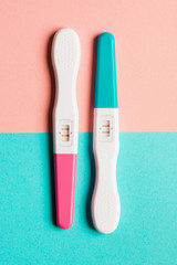Positive pink and blue plastic pregnancy test on pink background