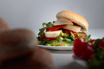 Sandwich with mozzarella, tomato and salad on the kitchen table.