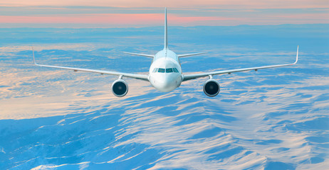 Fototapeta na wymiar Airplane is flying over low clouds and snowy mountains