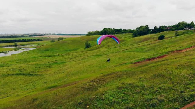 Green fields with a person running up and flying the parafoil