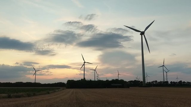 Wind turbines for green energy generation in fast motion time-lapse at dusk in Burgenland plains.